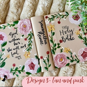 May include: Tan Bible cover with pink floral design. The cover features the text "God is within her, she will not fail" and "The Holy Bible". The spine is inscribed with "Samantha Renee".