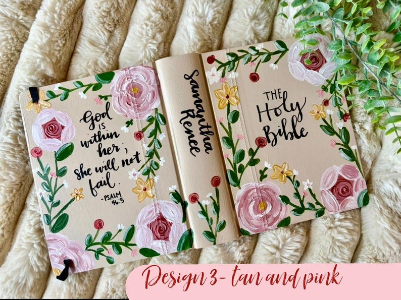 May include: Tan Bible cover with pink floral design. The cover features the text "God is within her, she will not fail" and "The Holy Bible". The spine is inscribed with "Samantha Renee".