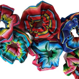 May include: Six colorful hair scrunchies with a striped pattern. The scrunchies are made of fabric and have a gathered look.