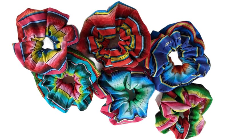 May include: Six colorful hair scrunchies with a striped pattern. The scrunchies are made of fabric and have a gathered look.