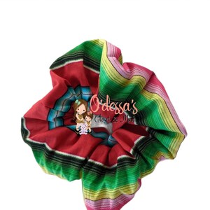 May include: A red, green, yellow, and pink striped scrunchie with the text "Odessa's Closet & More" in black.