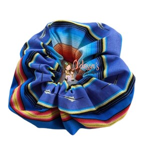 May include: A blue, yellow, red, and white patterned scrunchie. The pattern is reminiscent of a traditional Mexican blanket.