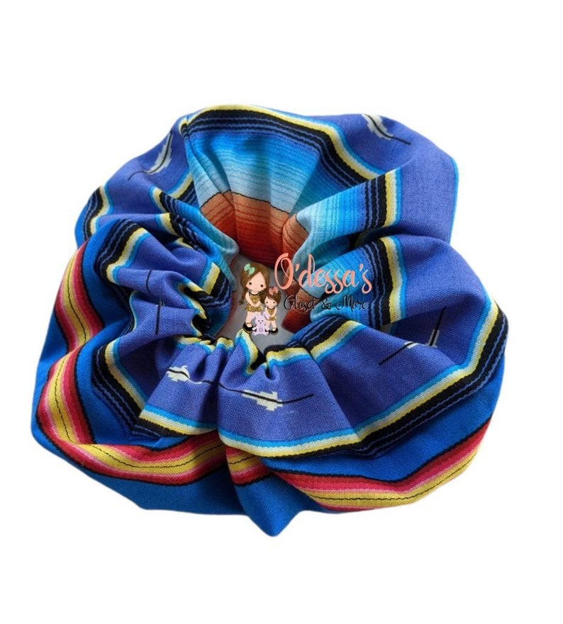 May include: A blue, yellow, red, and white patterned scrunchie. The pattern is reminiscent of a traditional Mexican blanket.