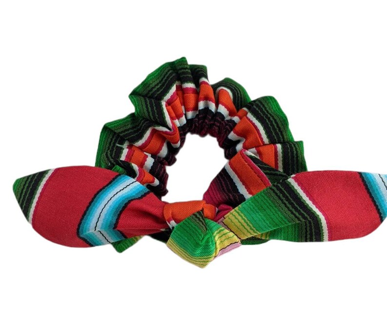 Puede incluir: Una colorida scrunchie con lazo, con un vibrante estampado de rayas en rojo, verde, naranja y azul. La scrunchie est&aacute; dise&ntilde;ada con un estilo textil tejido tradicional, perfecta para a&ntilde;adir un toque de color a cualquier peinado.
