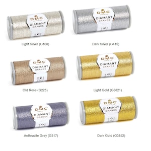 Könnte beinhalten: Sechs Spulen DMC Diamant Grande Stickgarn in verschiedenen Metallic-Farben: Hell Silber, Dunkel Silber, Altrosa, Hell Gold, Anthrazit Grau und Dunkel Gold. Jede Spule trägt das DMC-Logo und den Text "Diamant Grande" aufgedruckt.
