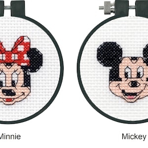 May include: Two embroidery hoops with cross-stitch designs of Mickey Mouse and Minnie Mouse. Mickey Mouse is wearing his signature red shorts and yellow shoes. Minnie Mouse is wearing a red polka dot bow. The hoops are labeled "Mickey" and "Minnie".