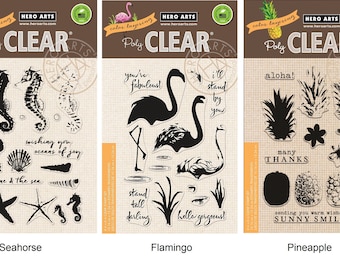 May include: Three clear stamp sets featuring a seahorse, flamingo, and pineapple. Each set includes multiple stamps with various designs and phrases. The stamps are labeled "Poly Clear" and "Hero Arts".