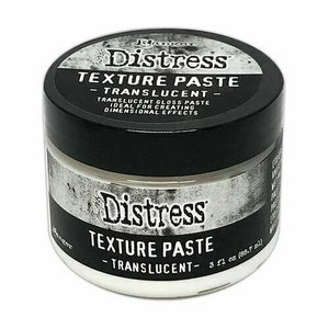 Può includere: Un barattolo bianco di pasta per texture Distress traslucida, una pasta lucida ideale per creare effetti dimensionali. Il barattolo è etichettato con il nome del marchio "Ranger" e il nome del prodotto "Distress Texture Paste - Translucent - 3 fl oz (88.7 ml)".