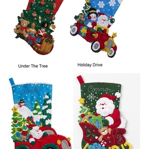 May include: Four felt Christmas stockings with different designs. The first stocking is red with a green Christmas tree and the text "Under The Tree". The second stocking is blue with a snowman and Santa in a red car and the text "Holiday Drive". The third stocking is blue with a snowman and Santa in a red truck and the text "The Christmas Drive". The fourth stocking is green with Santa in a sleigh and the text "Santa's Sleigh".
