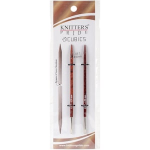 Peut inclure: Une paire d'aiguilles à tricoter en bois brun avec des pointes argentées. Les aiguilles sont étiquetées "US 7 - 4,50 mm" et sont emballées dans une pochette en plastique transparente avec le logo Knitter's Pride et les mots "Cubics" et "Square Cross Section".