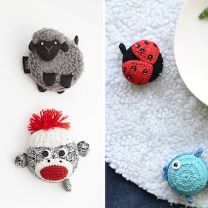 Könnte beinhalten: Ein Set an gehäkelten Messbändern in Tierform. Das Set enthält ein Schaf, einen Affen, einen Marienkäfer, einen Fisch und eine Sonnenblume.