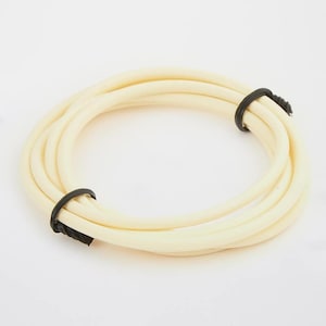 May include: Coiled, off-white rubber tubing, secured with two black zip ties. The tubing is arranged in a circular shape, with the zip ties holding the coil together. The rubber appears smooth and flexible, suitable for various applications.