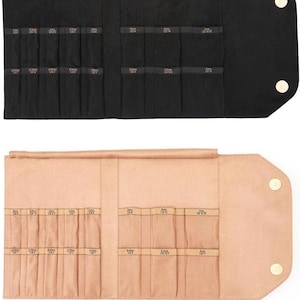 May include: Two open, rolled-up cases for storing jewelry. The case on top is black with gold snaps and the case on the bottom is a light peach color with gold snaps. Both cases have rows of slots labeled with different sizes in millimeters.
