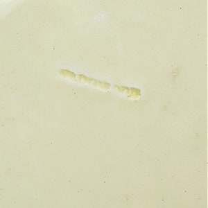 May include: A close-up of a light beige surface with a thin, light yellow line running across it.