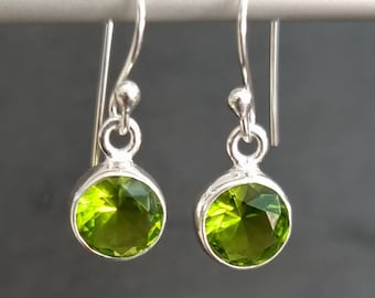 Peut inclure: Une paire de boucles d'oreilles pendantes en argent avec des pierres précieuses rondes en péridot vert.