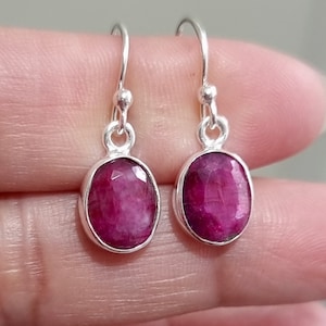 Könnte beinhalten: Ein Paar silberne Ohrhänger mit ovalen rosafarbenen Rubin-Edelsteinen.