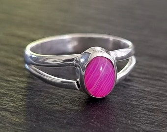 Könnte beinhalten: Ein silberner Ring mit einem rosafarbenen ovalen Edelstein. Der Ring hat ein Doppelband-Design.