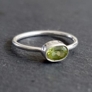 May include: A silver ring with a light green oval gemstone.