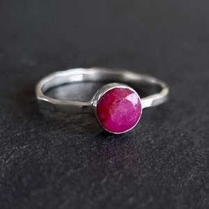 May include: A silver ring featuring a vibrant pink ruby gemstone. The ring has a hammered finish.