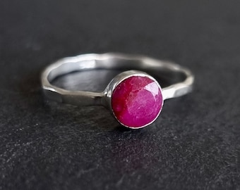 May include: A silver ring with a bright pink ruby gemstone. The ring has a hammered texture.