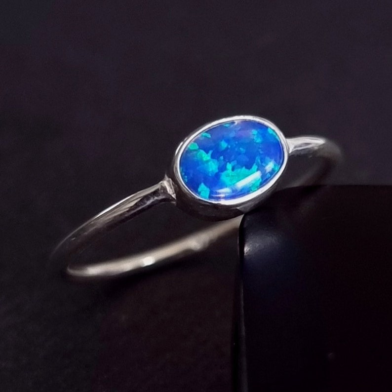 May include: A silver ring with a blue oval opal gemstone.