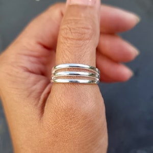 May include: A silver thumb ring with four bands.