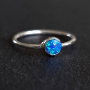 Peut inclure: Une bague en argent avec une pierre précieuse en opale bleue. La bague est simple et élégante.