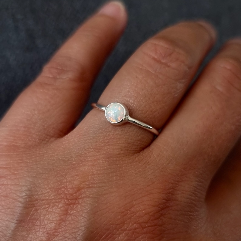 K&ouml;nnte beinhalten: Ein zarter Silberring mit einem wei&szlig;en Opal-Edelstein. Der Ring ist schlicht und elegant, perfekt f&uuml;r den Alltag.