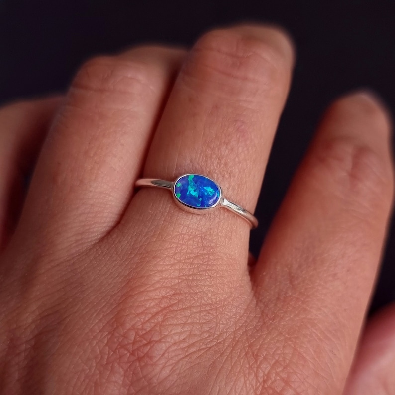 May include: A silver ring with a blue oval opal gemstone.