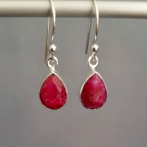 Könnte beinhalten: Ein Paar silberne Ohrhänger mit tropfenförmigen Rubinen.