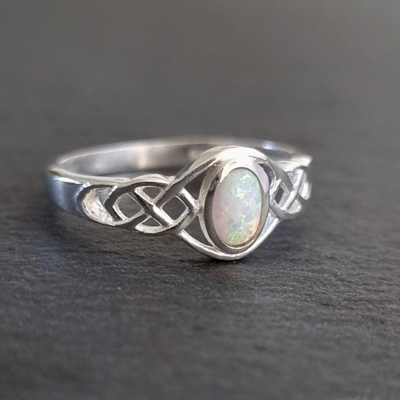 May include: A silver ring with a Celtic knot design and an oval opal gemstone.