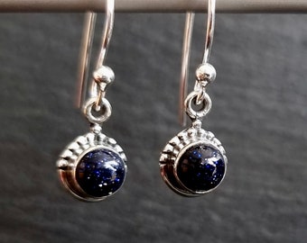 May include: A pair of silver dangle earrings with blue star dust stone accents.