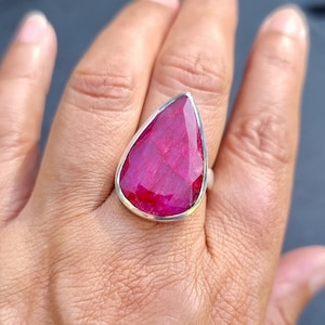 Peut inclure: Une bague en argent sterling avec une pierre de rubis en forme de larme. Le rubis est de couleur rouge foncé et a une taille facetée.