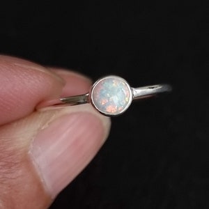 K&ouml;nnte beinhalten: Ein silberner Ring mit einem wei&szlig;en Opal-Edelstein. Der Ring ist schlicht und elegant.