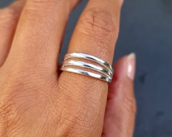 May include: A silver ring with four bands stacked on top of each other.