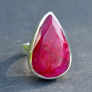 May include: A teardrop-shaped ruby ring set in sterling silver. The ruby is a deep red colour and has a faceted cut.