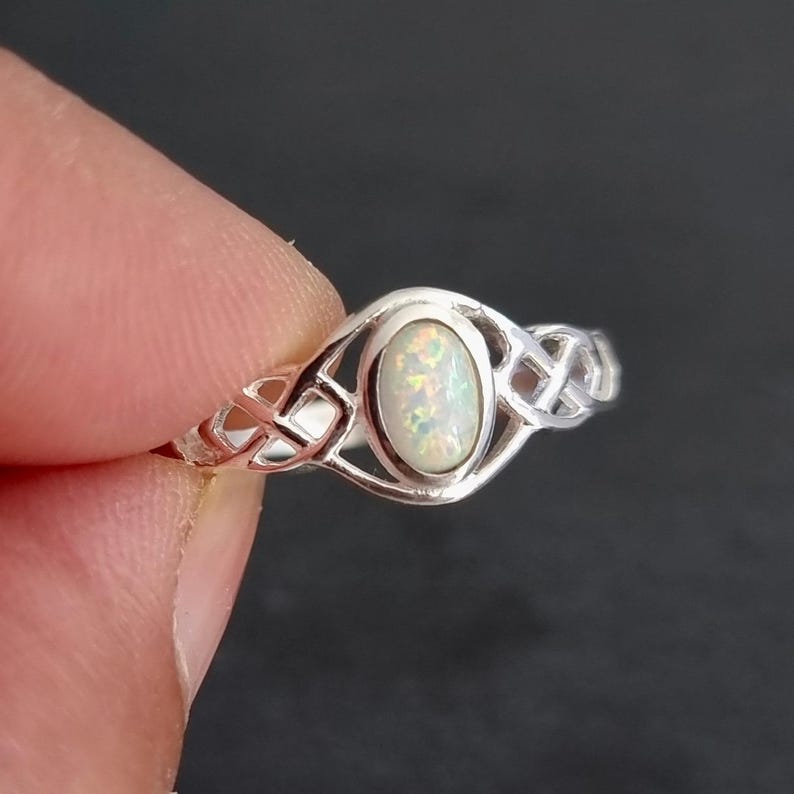 May include: A silver ring with a white opal gemstone set in a Celtic knot design.