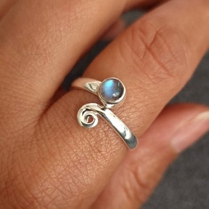 May include: A silver ring with a blue labradorite gemstone. The ring has a unique design with a swirl on one side.