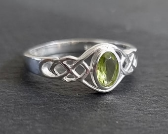 May include: A silver ring with a Celtic knot design and a green oval gemstone.