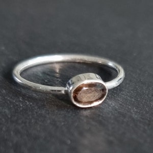 May include: A silver ring with a brown oval gemstone.