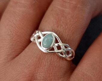 May include: A silver ring with a Celtic knot design and a light blue oval gemstone.