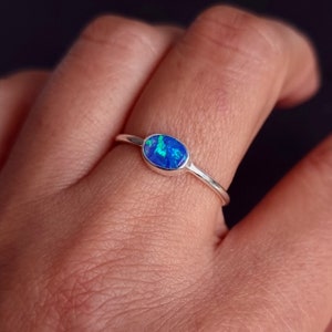 May include: A silver ring with a blue oval opal gemstone.