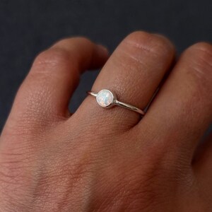 K&ouml;nnte beinhalten: Ein silberner Ring mit einem wei&szlig;en Opal-Edelstein. Der Ring ist schlicht und zart, perfekt f&uuml;r den t&auml;glichen Gebrauch.