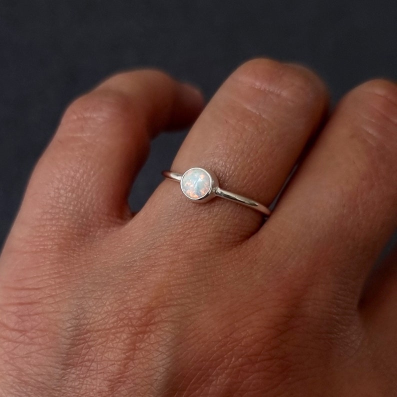 K&ouml;nnte beinhalten: Ein silberner Ring mit einem wei&szlig;en Opal-Edelstein. Der Ring ist schlicht und zart, perfekt f&uuml;r den t&auml;glichen Gebrauch.