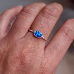 May include: A silver ring with a blue oval opal gemstone.