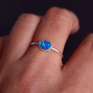 May include: A silver ring with an oval-shaped blue opal gemstone.