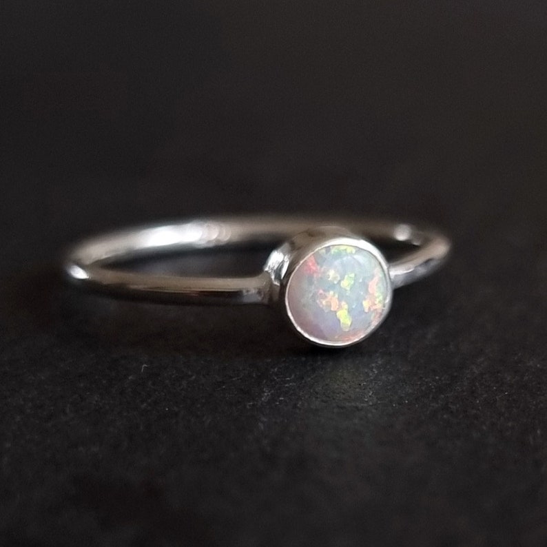 K&ouml;nnte beinhalten: Ein silberner Ring mit einem wei&szlig;en Opal-Edelstein. Der Ring ist schlicht und elegant.