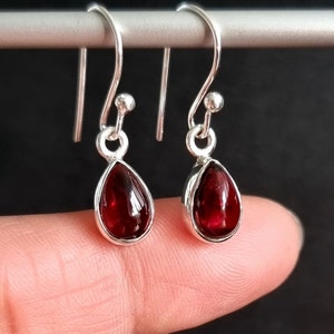 Peut inclure: Une paire de boucles d'oreilles pendantes en argent avec des pierres précieuses rouges en forme de goutte.