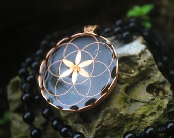 May include: A black and copper pendant necklace with a flower of life design. The pendant is round and has a copper wire design on a black background.