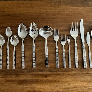 May include: A set of 11 silver-toned flatware pieces with ornate floral designs. The set includes spoons, forks, a serving spoon, a ladle, and a serving fork.